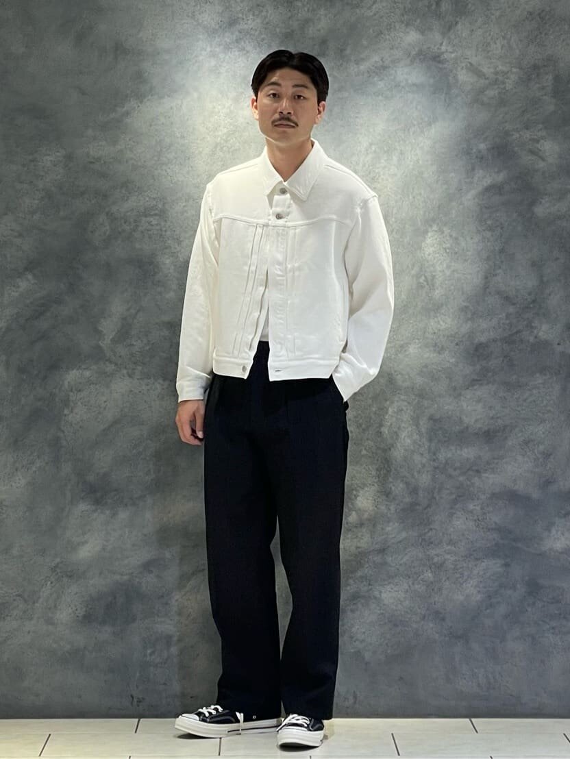 白のデニムブルゾンとツータックパンツを着た男性