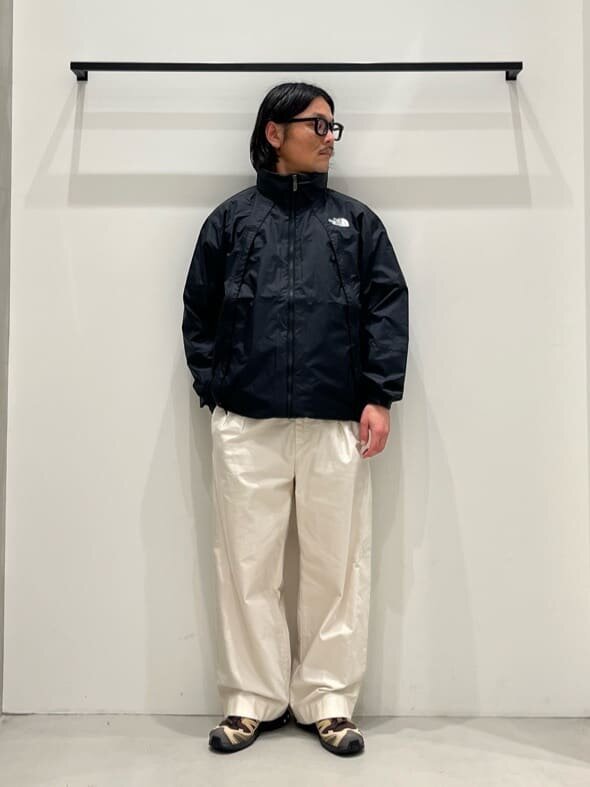黒のウインドブレーカーと白いパンツを着た男性