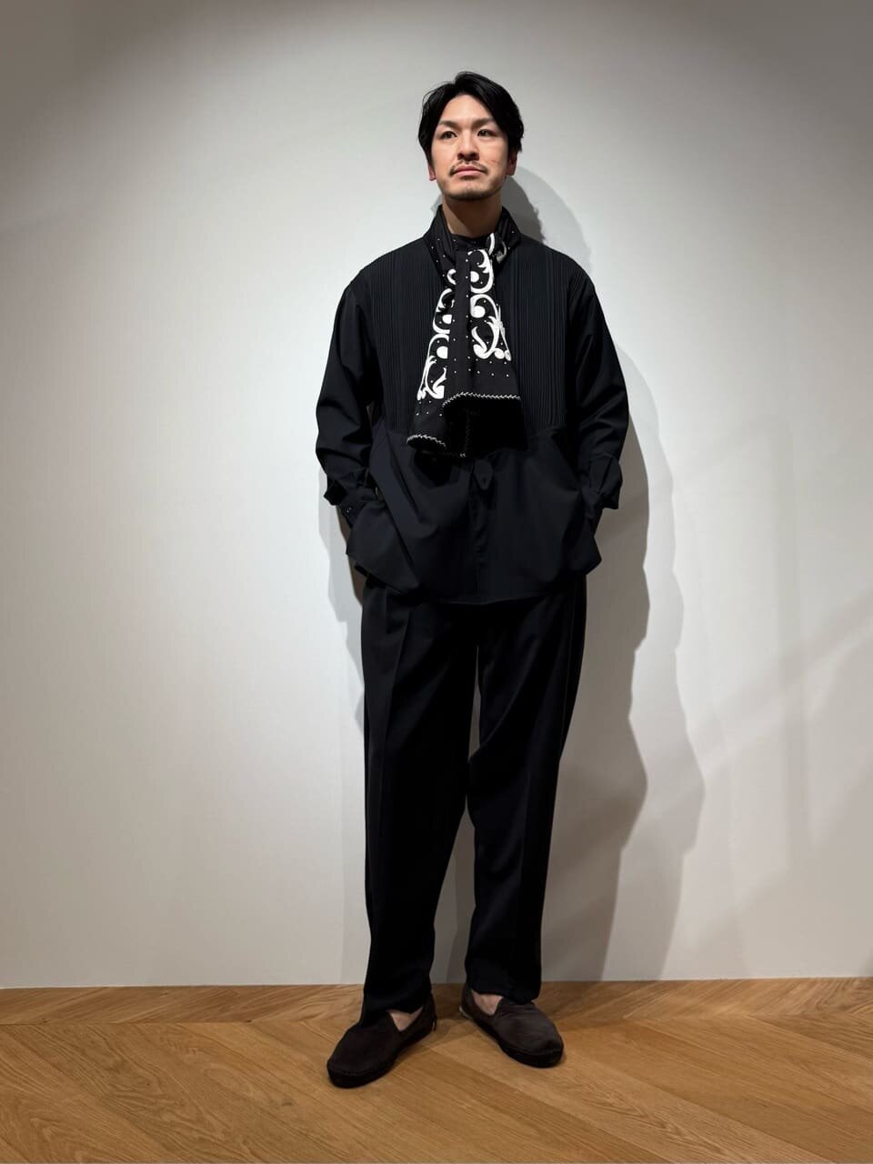 黒のシャツとテーパードパンツを着た男性