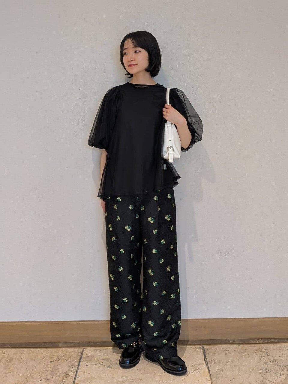 ボリュームスリーブカットソーと花柄パンツを着た女性