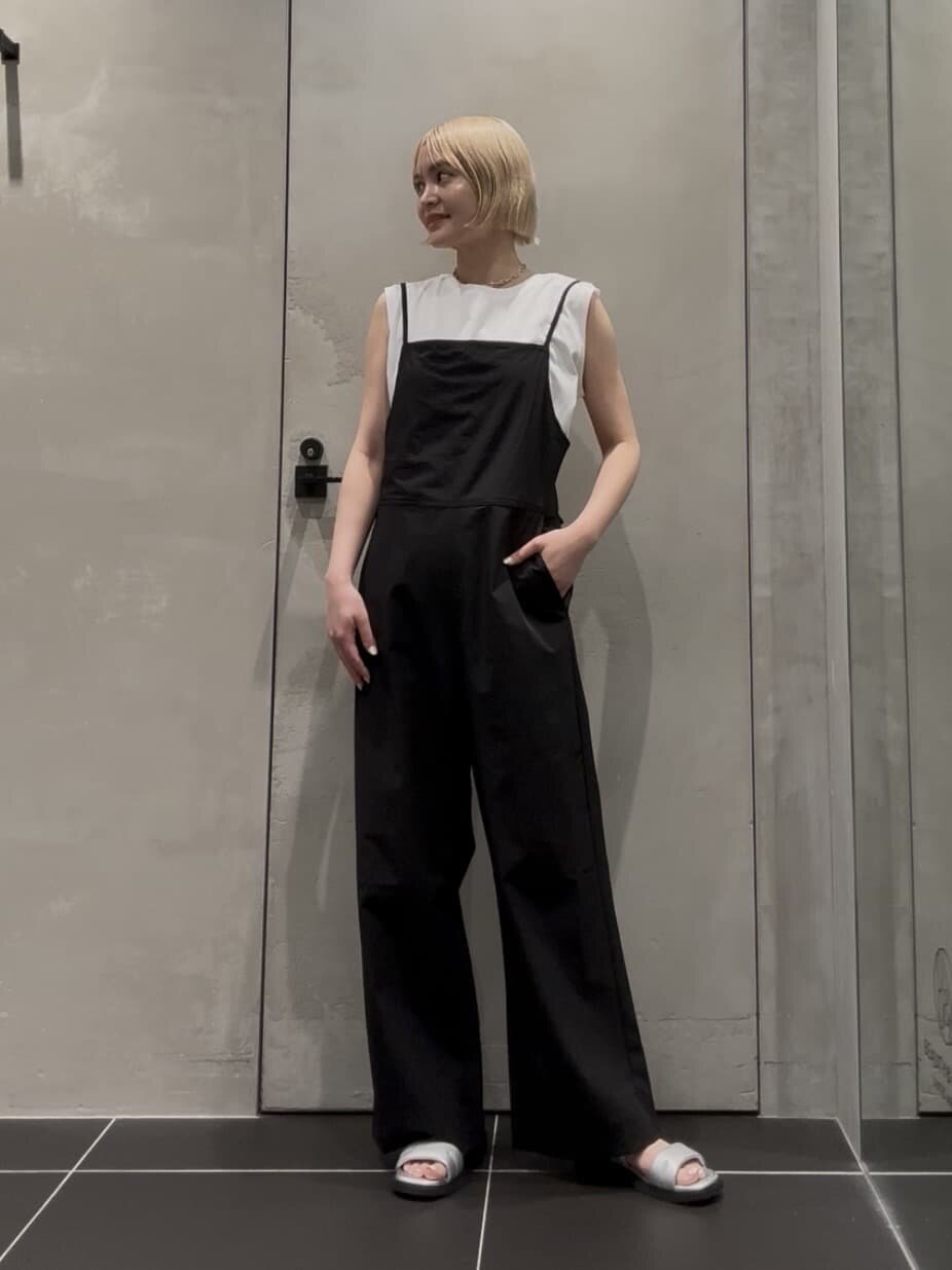ノースリーブカットソーとキャミソールサロペットを着た女性