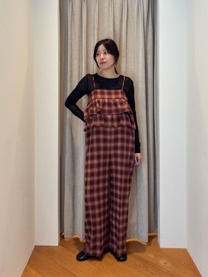 ロングスリーブカットソーとチェック柄サロペットを着た女性