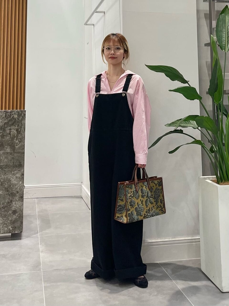 ストライプ柄シャツとデニムサロペットを着た女性