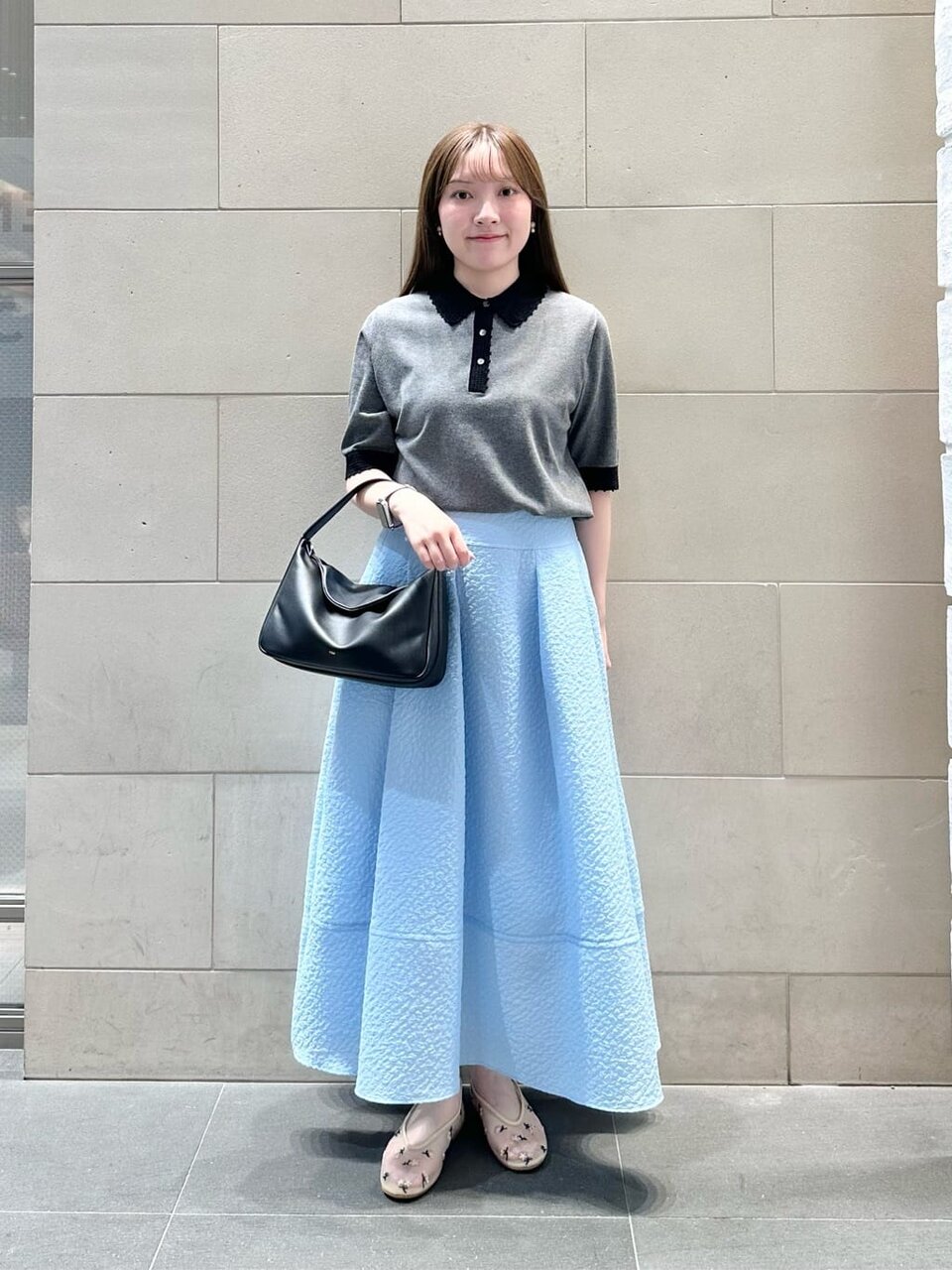 水色のスカートにグレーのポロニットをあわせた女性