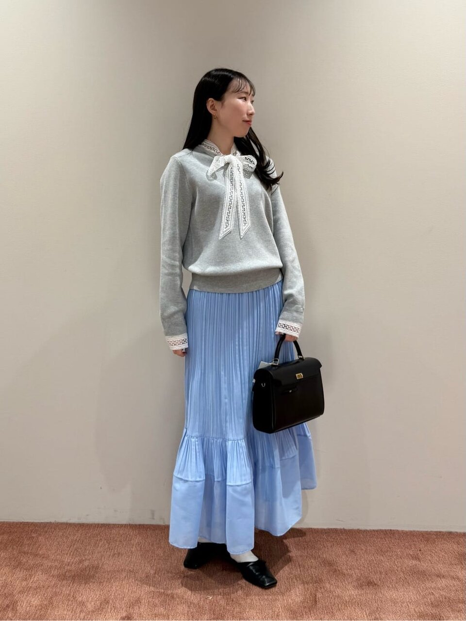 水色のスカートにグレーのニットをあわせた女性