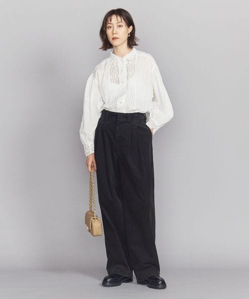 白いブラウスとワイドパンツの女性