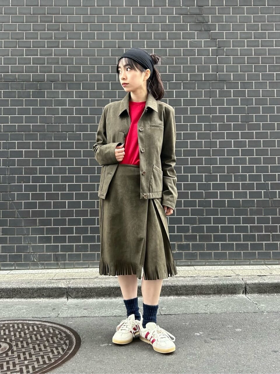 赤のインナーにカーキのセットアップを着た女性