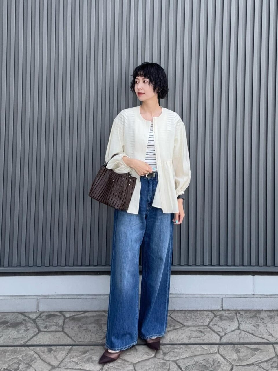 ノーカラージャケットとデニムパンツを着た女性