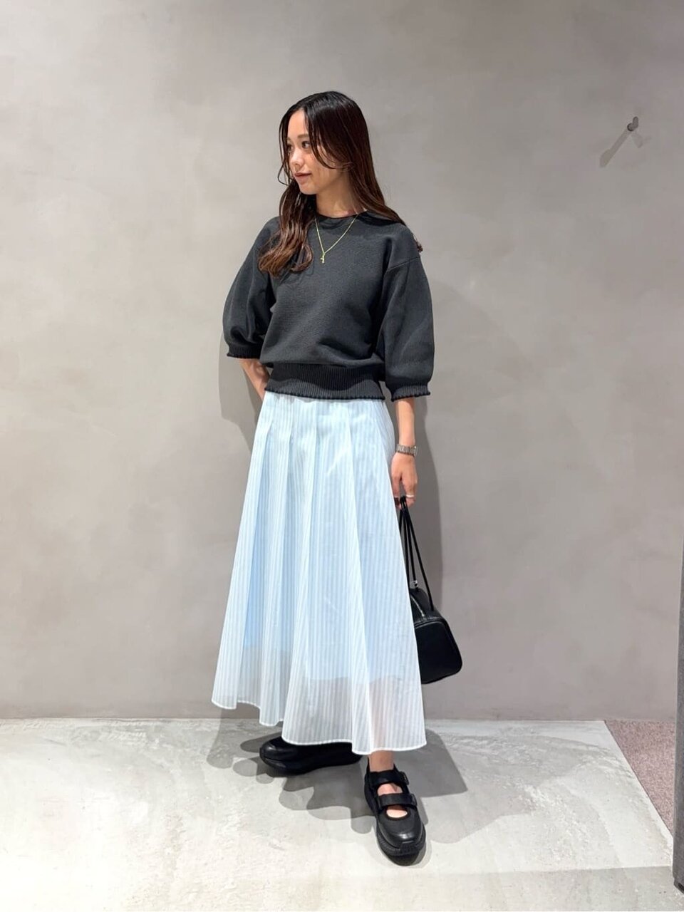 パフスリーブニットとシアースカートを着た女性