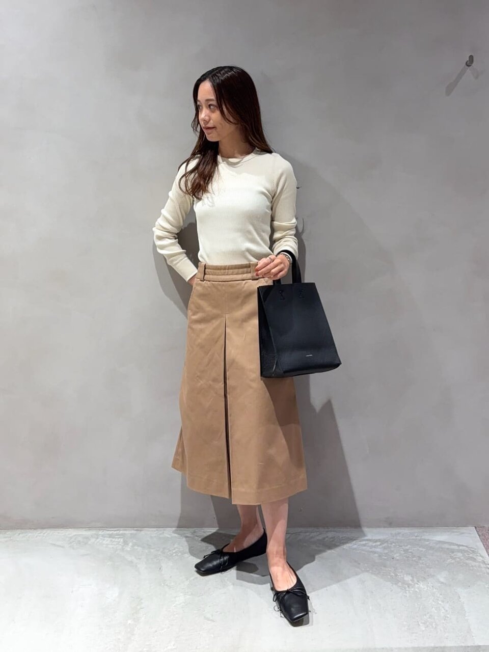 リブカットソーとプリーツスカートを着た女性