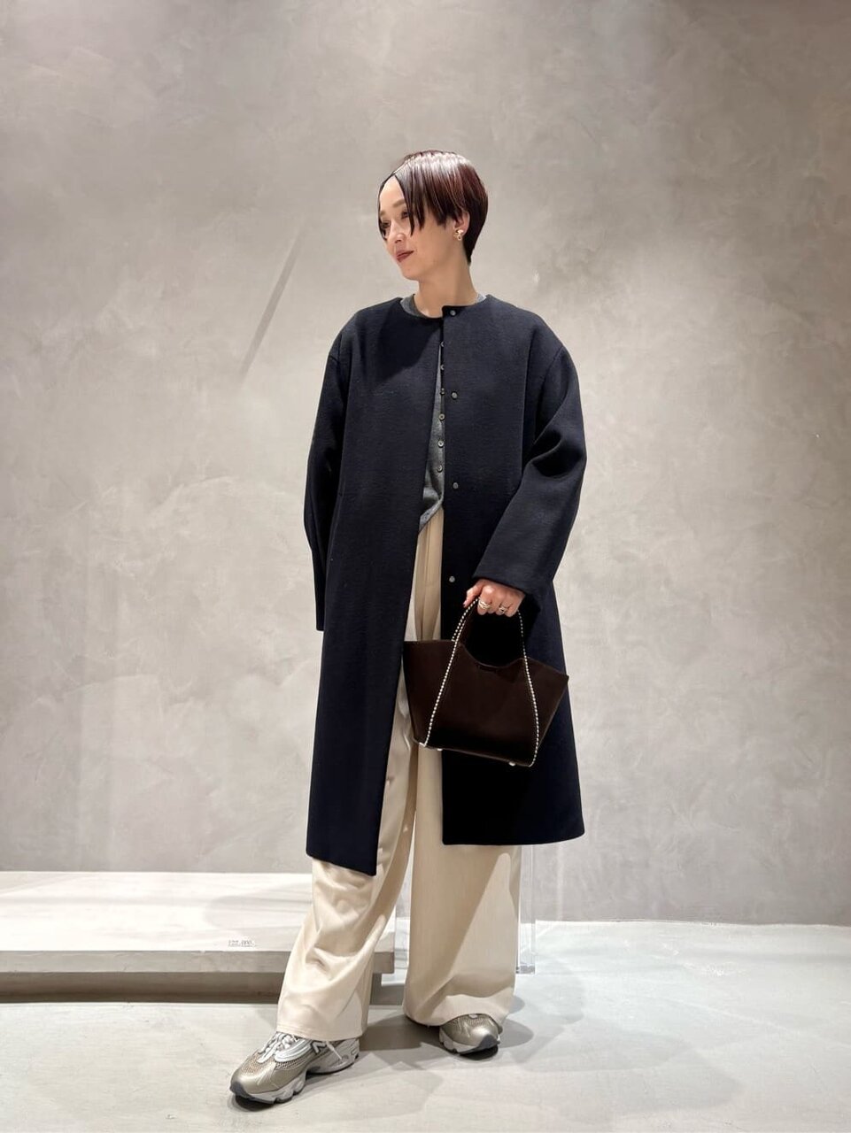 ノーカラーコートとワイドパンツを着た女性