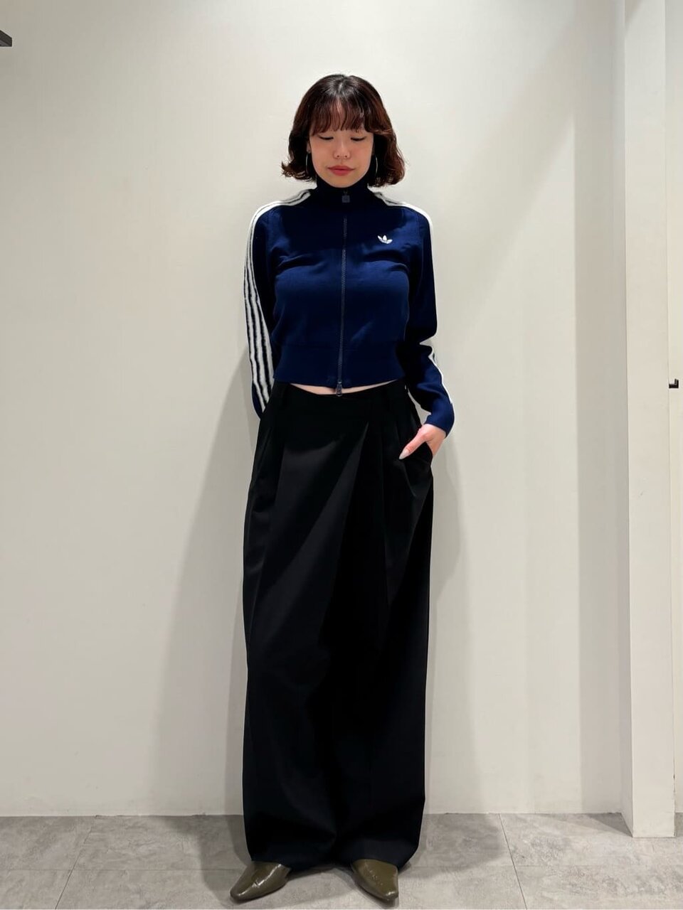 トラックジャケットとポインテッドトゥパンプスをあわせた女性