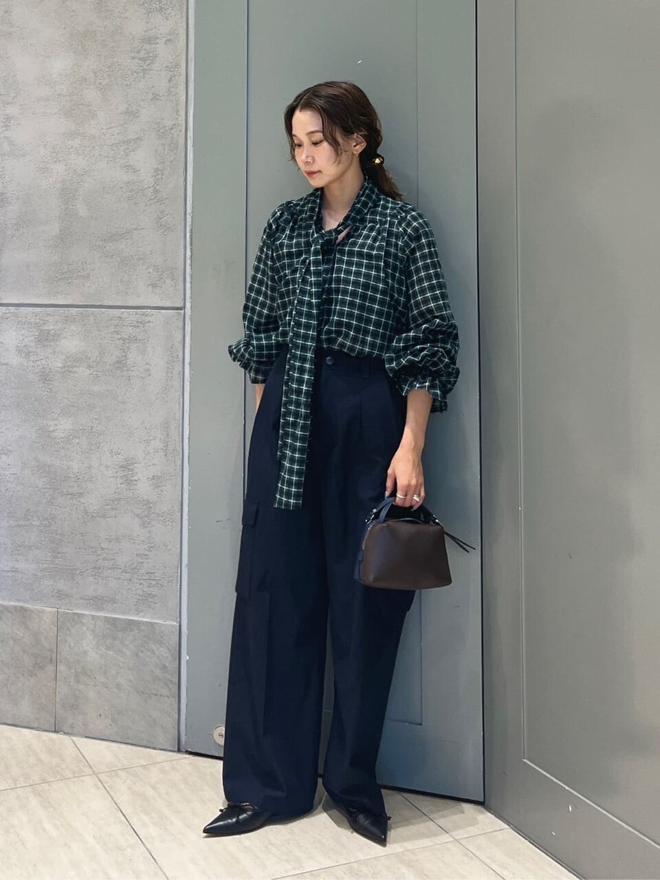 チェック柄シャツとポインテッドトゥパンプスをあわせた女性