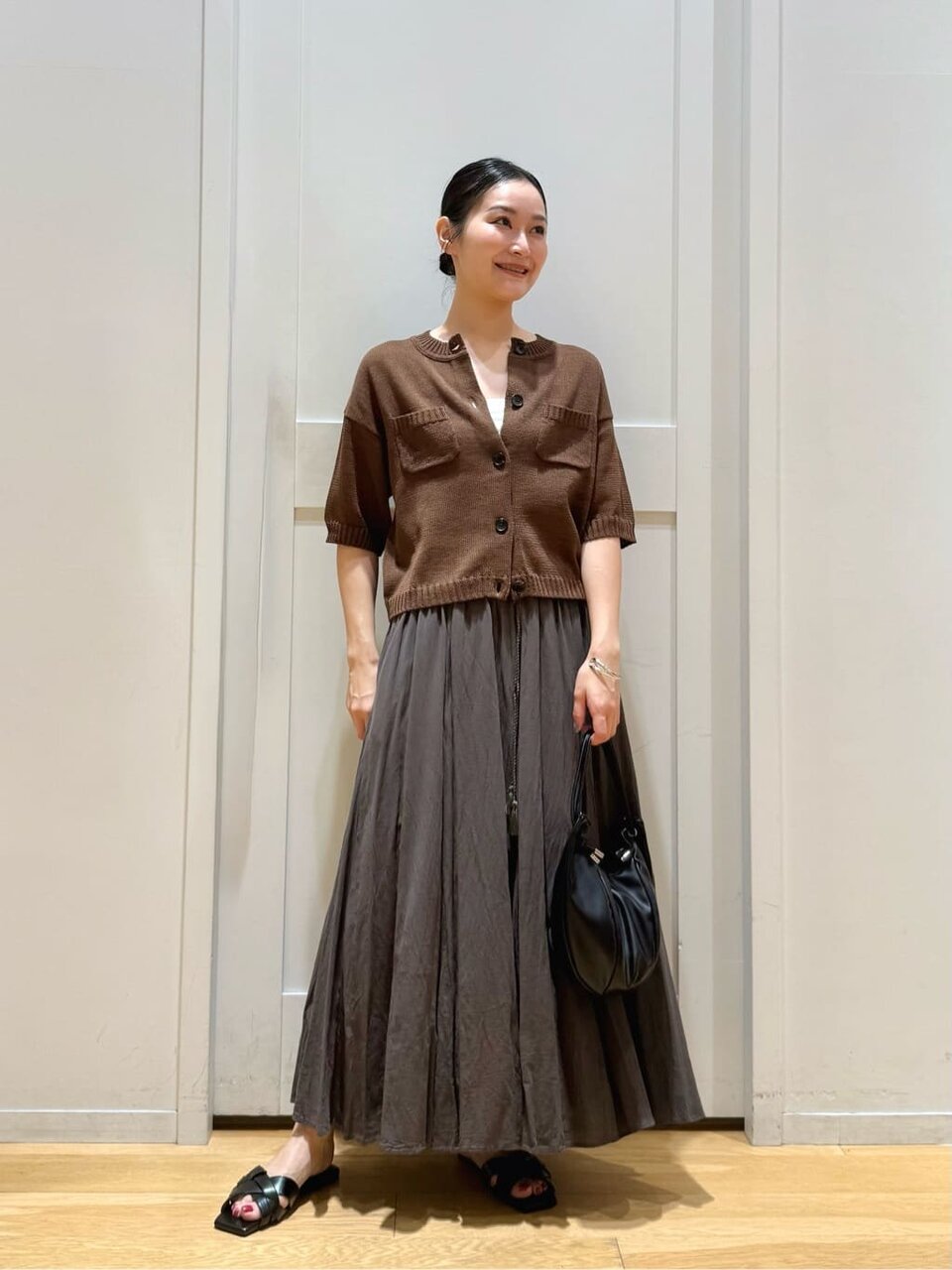 ハーフスリーブガーディガンとフレアスカートを着た女性