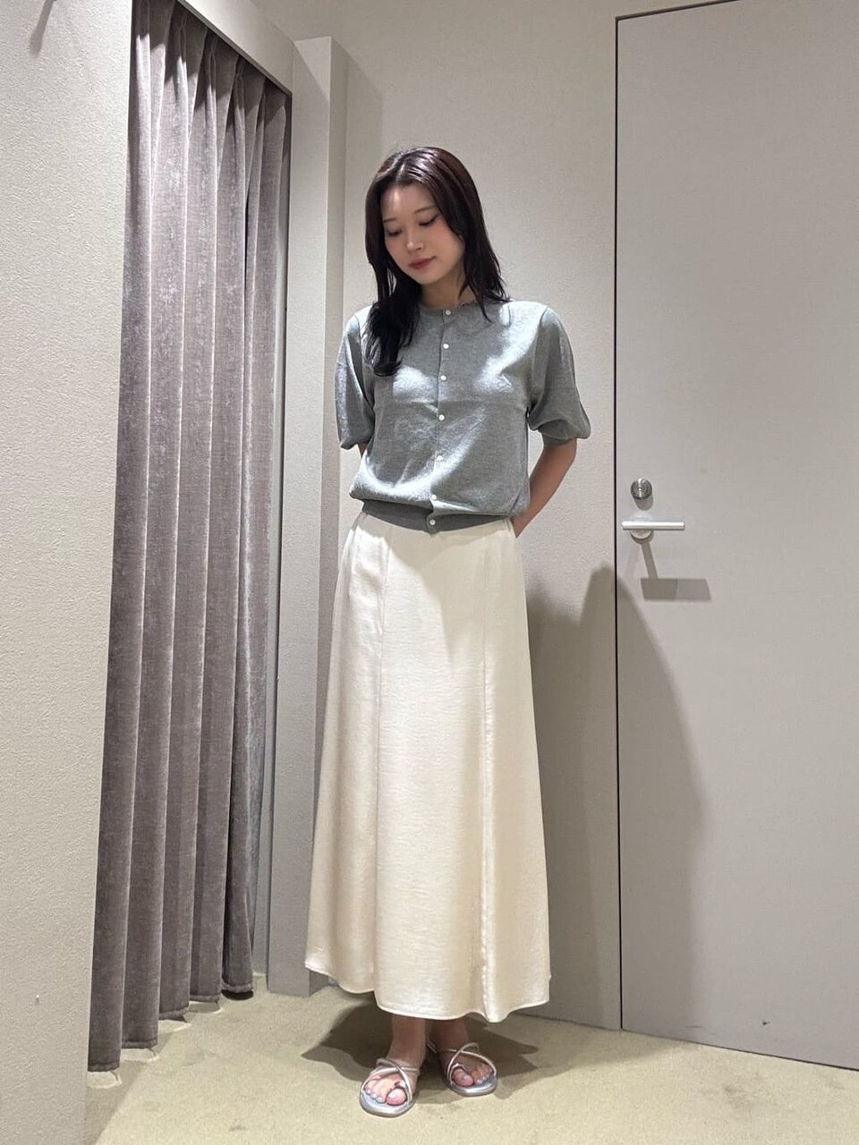 ラメカーディガンとサテンスカートを着た女性