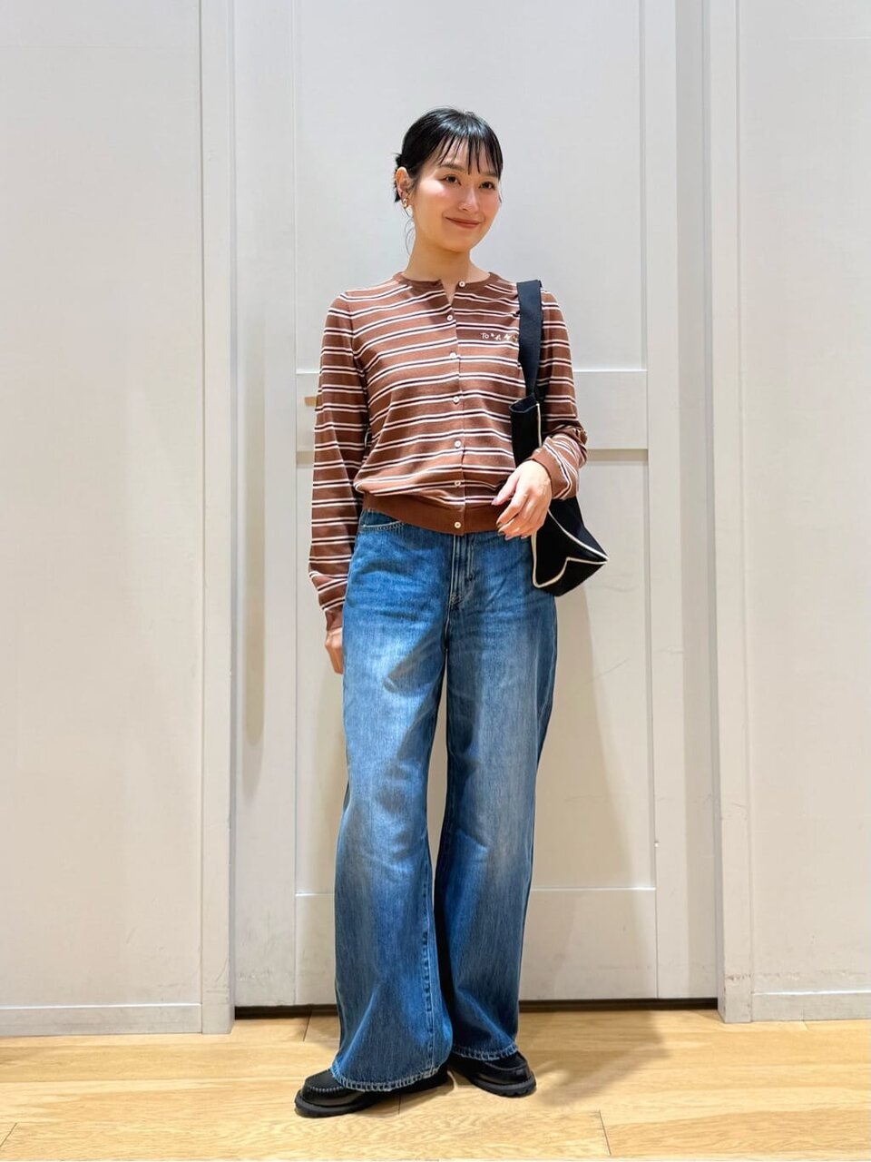 ボーダー柄カーディガンとデニムパンツを着た女性