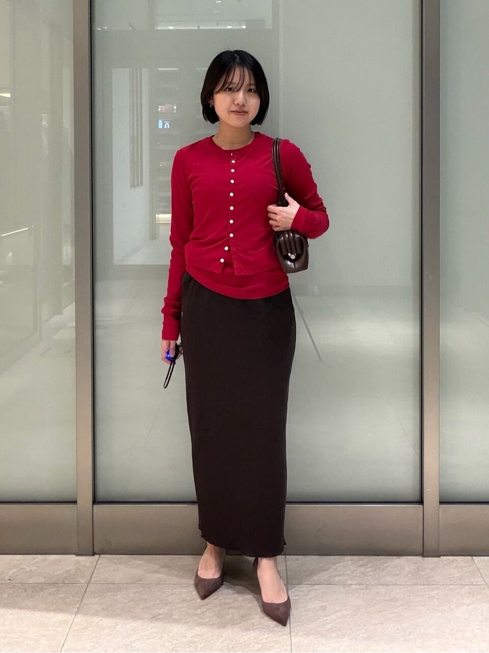 赤いカーディガンとアイラインスカートを着た女性