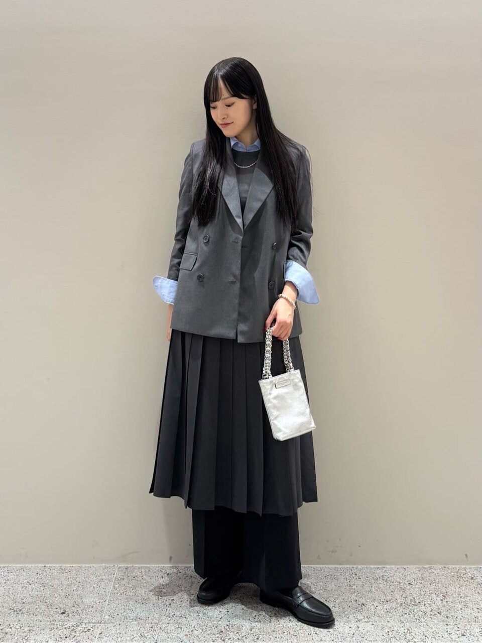 ダブルジャケットとプリーツスカートを着た女性