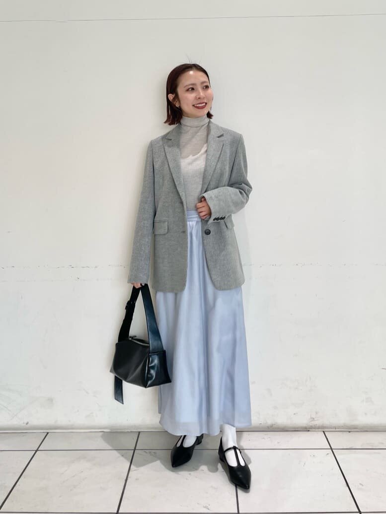 グレーのテーラードジャケットとギャザースカートを着た女性