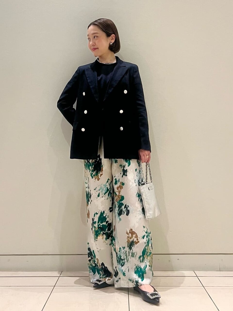 テーラードジャケットと花柄パンツを着た女性