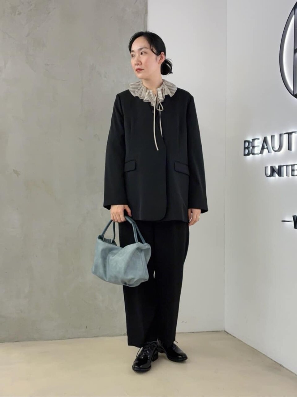 ノーカラージャケットとフリルカラーブラウスをあわせた女性