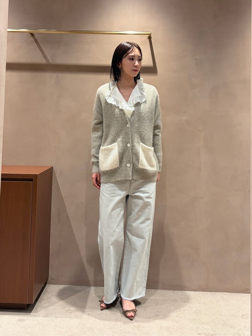 ニットカーディガンとデニムパンツを着た女性