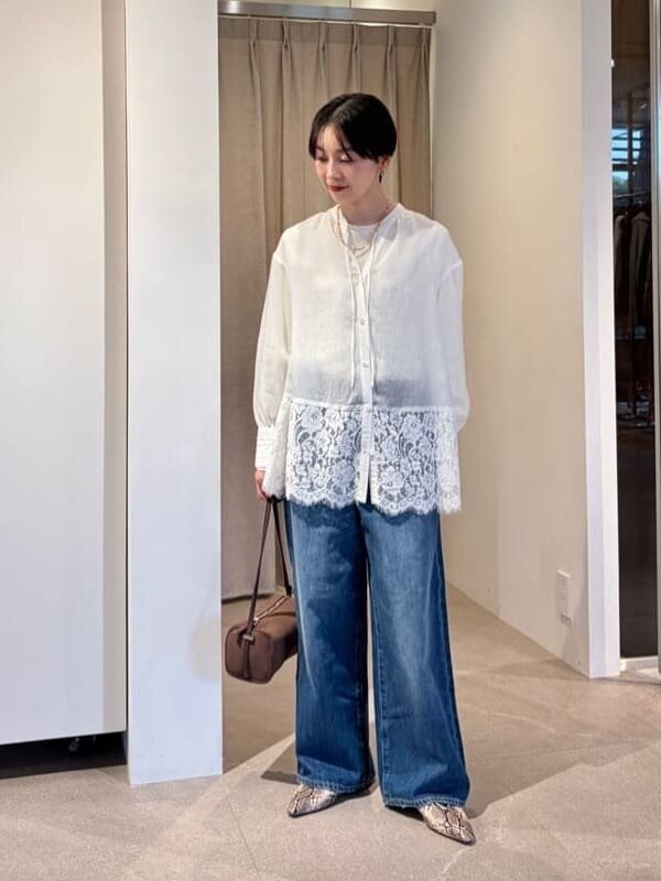 レースブラウスとデニムパンツを着た女性