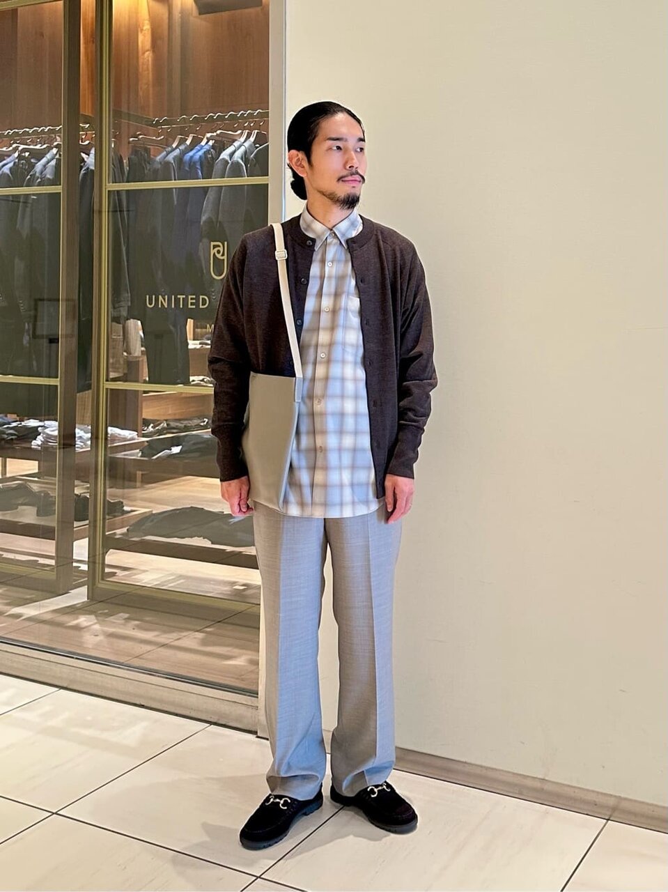 チェックシャツとカーディガンの秋服コーデの男性