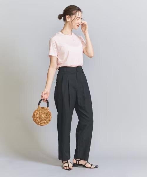 ピンクのTシャツと黒のハイウエストパンツを着た女性