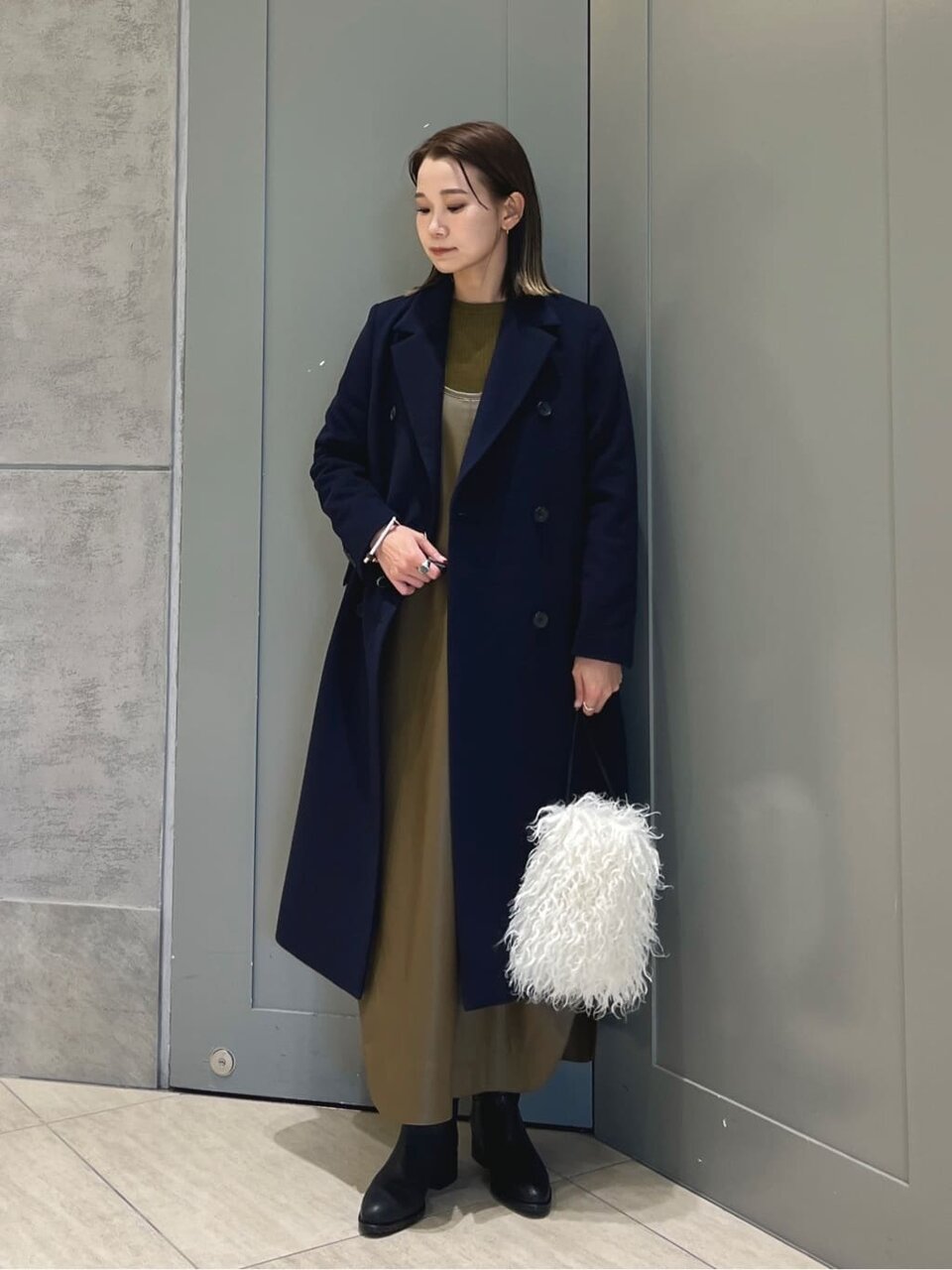 ワンピースとチェスターコートを着た女性