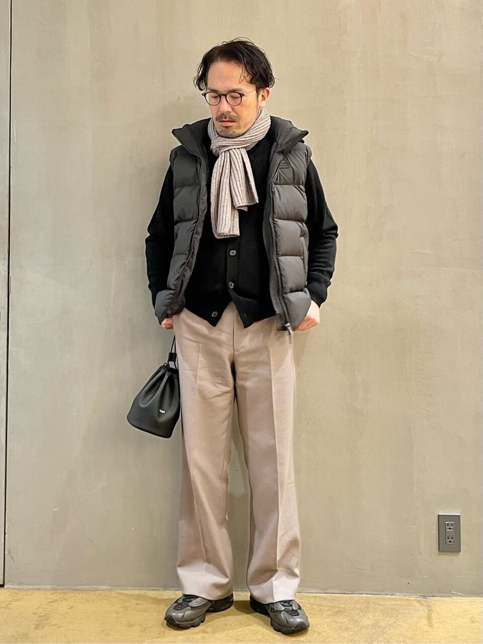 黒のダウンベストにパンツをあわせた男性