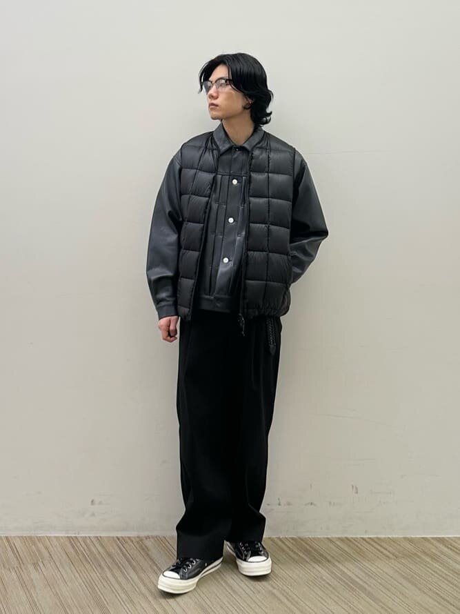 黒のダウンベストにジャケットをあわせた男性