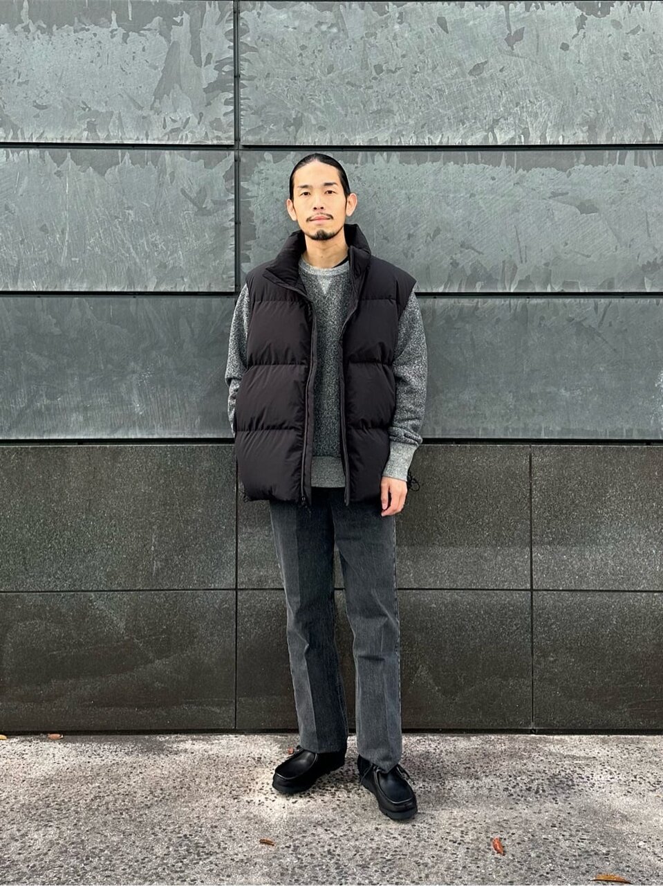 黒のダウンベストを着たきれいめコーデの男性