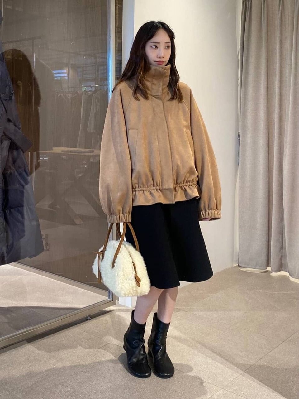 スエードライクブルゾンとニットワンピースを着た女性