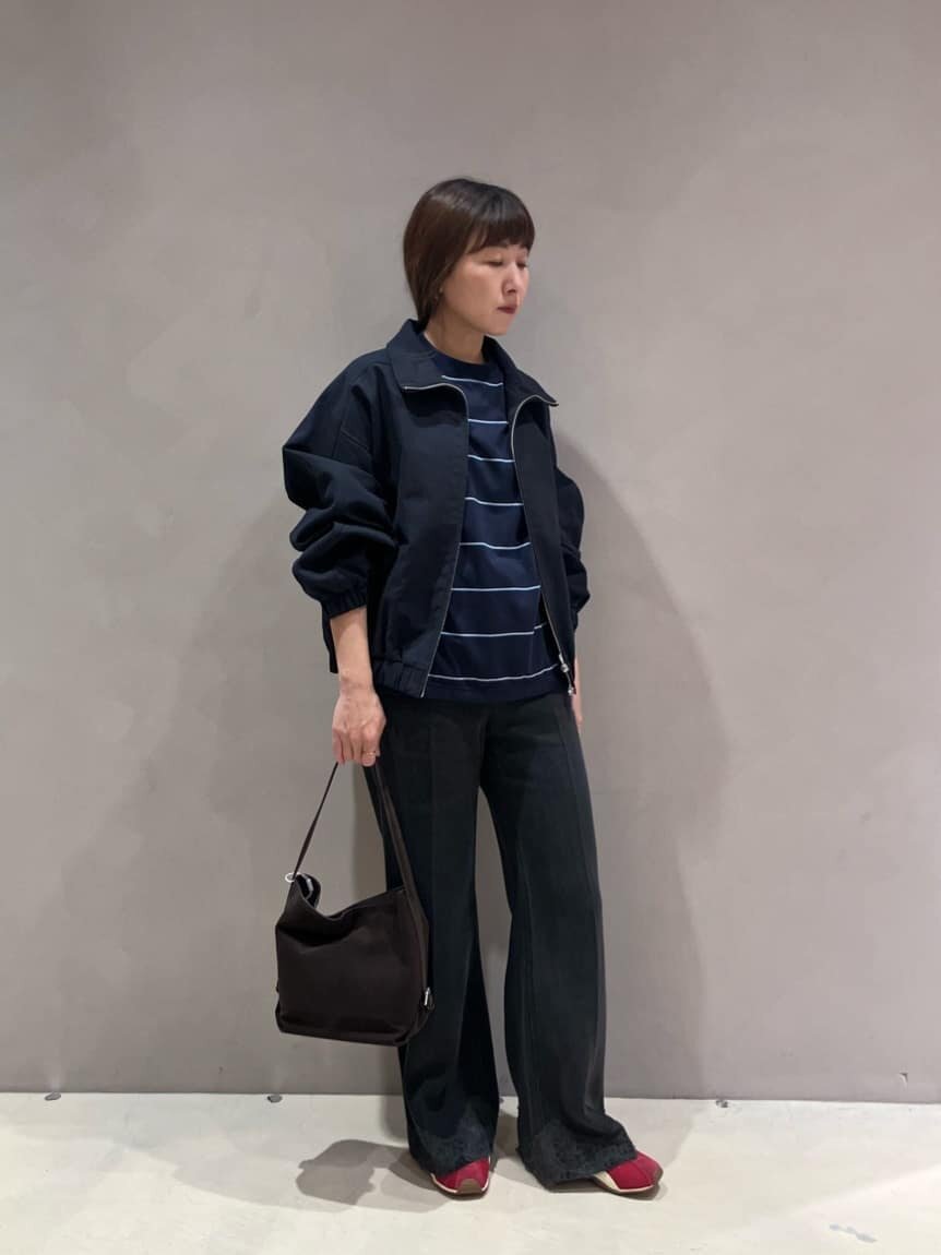 ジップアップブルゾンとデニムパンツを着た女性