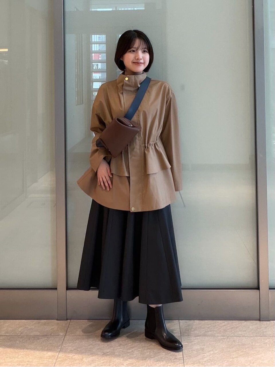ペプラムブルゾンとフレアスカートを着た女性