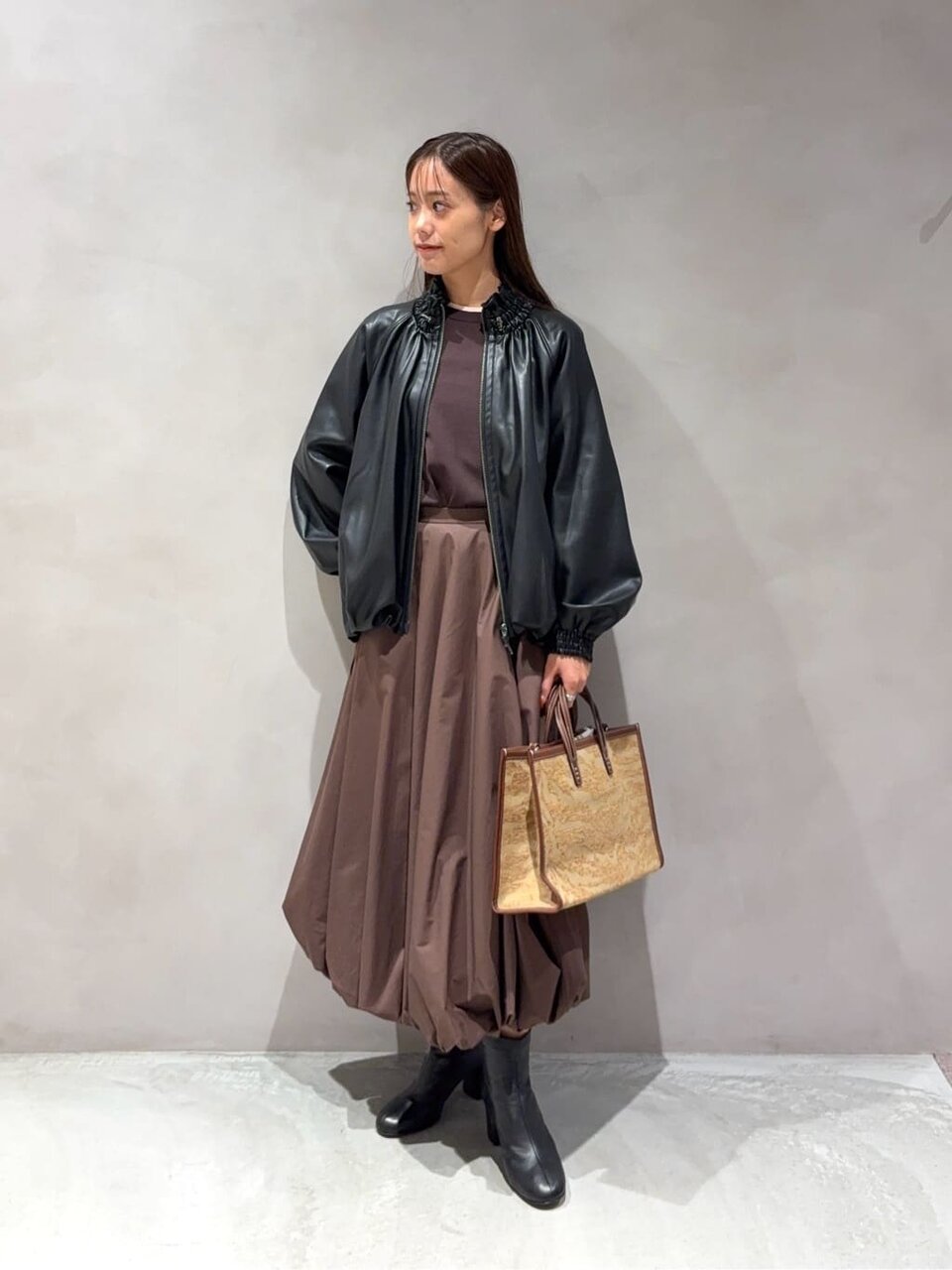 レザーライクブルゾンとバルーンスカートを着た女性