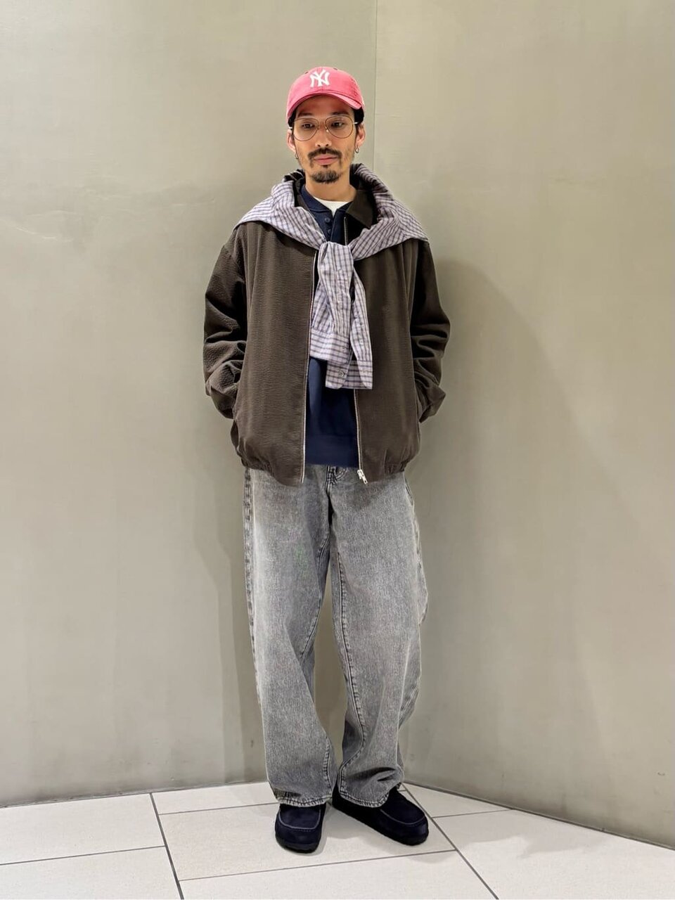 ジップブルゾンとデニムパンツを着た男性