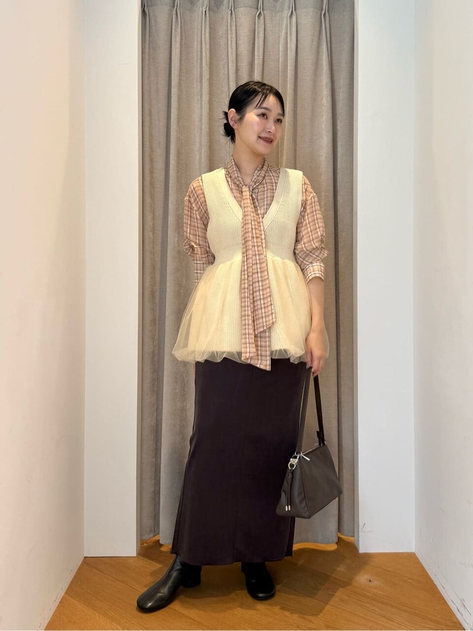 ボウタイブラウスとニットベストを着た女性