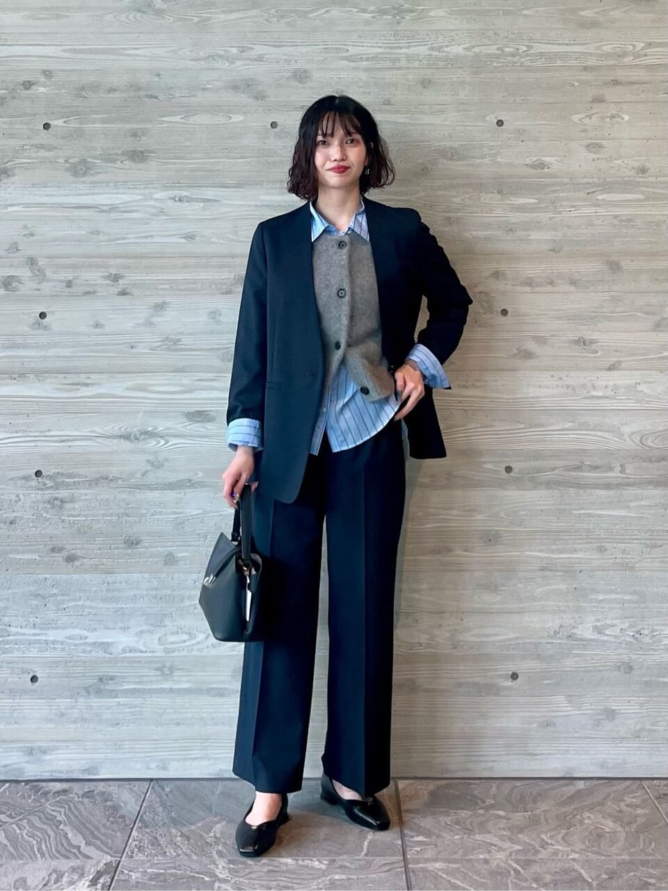 ノーカラージャケットとニットベストを着た女性