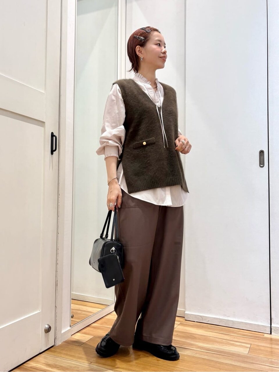 フリルネックブラウスとニットベストを着た女性
