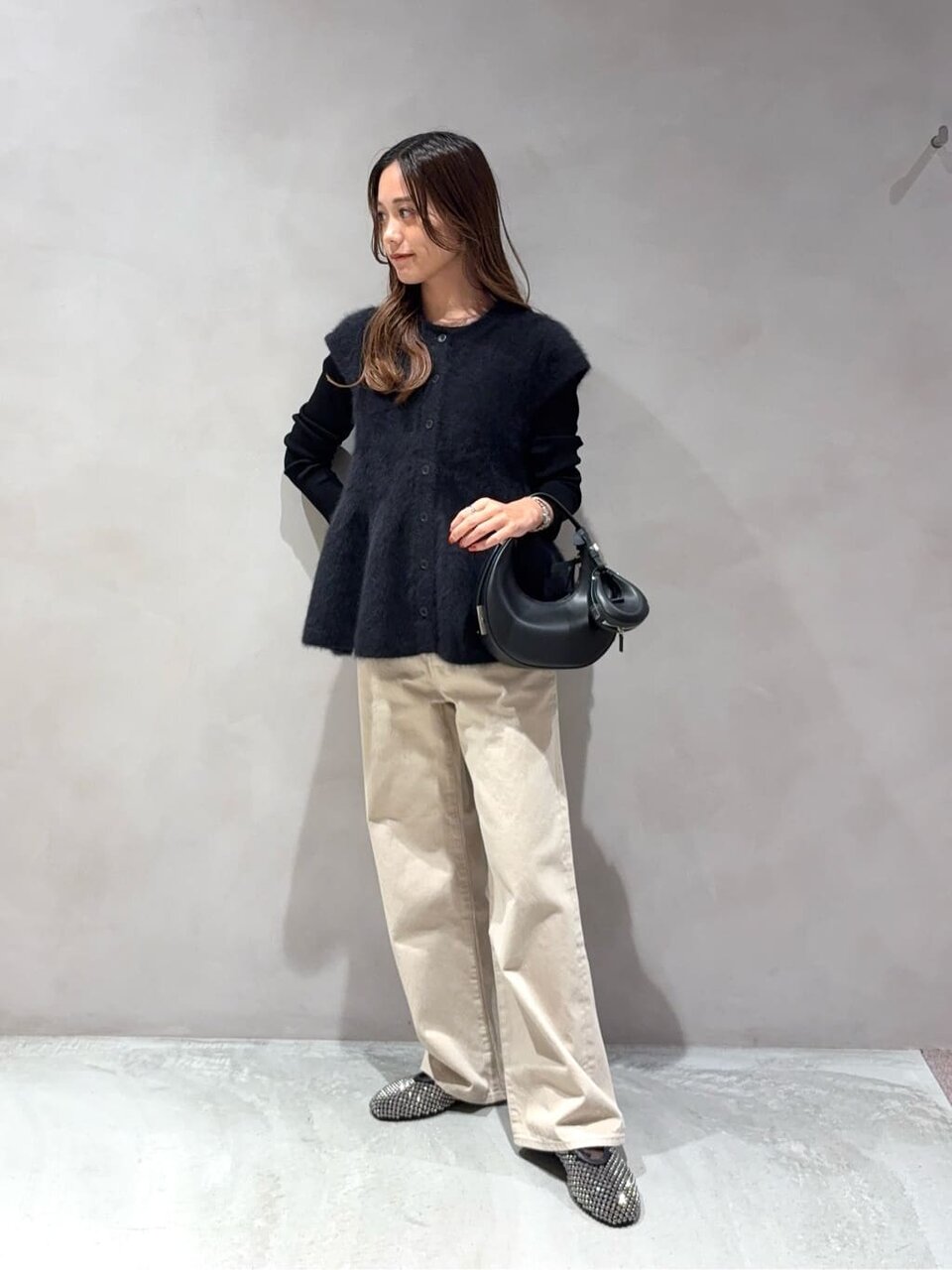 カットソーとペプラムニットベストを着た女性