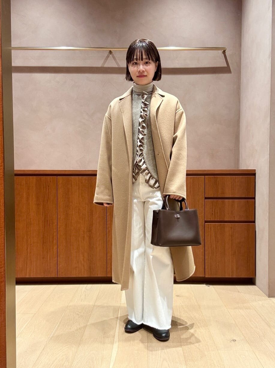 テーラードコートとフリルニットベストを着た女性