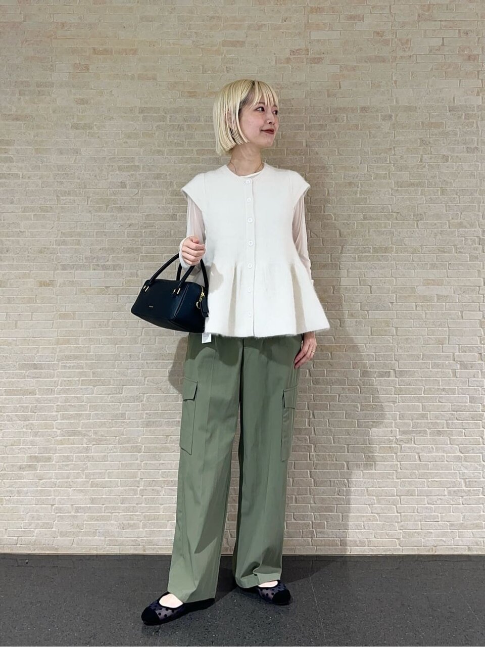 ペプラムニットベストとチュールカットソーを着た女性