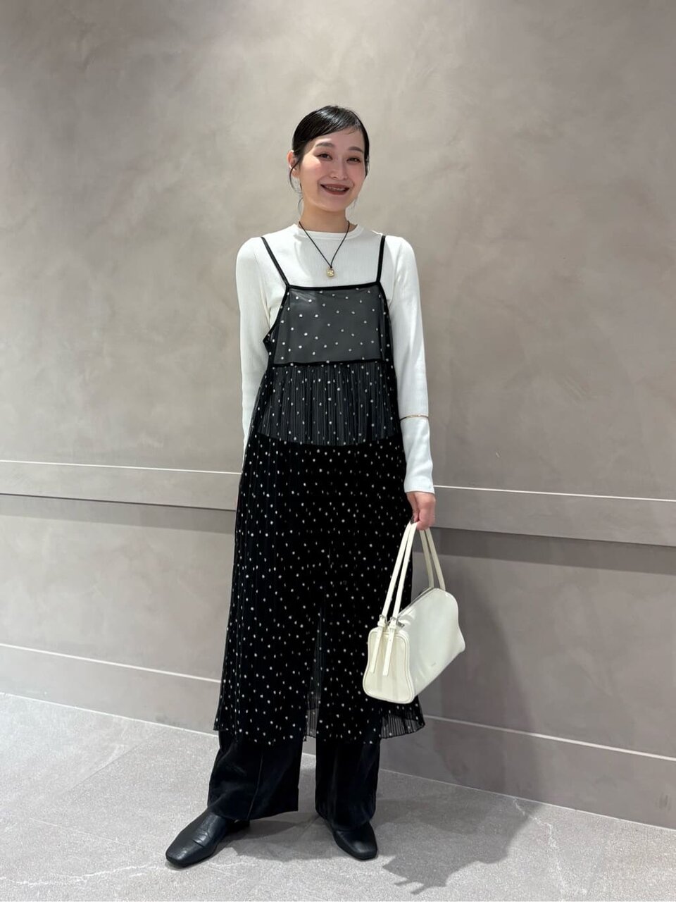 白ニットとキャミソールワンピースを着た女性