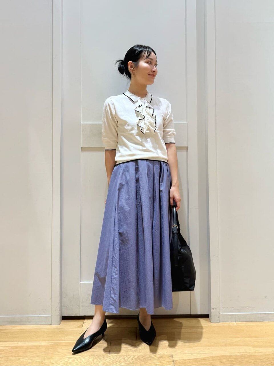 白ニットとフレアスカートを着た女性
