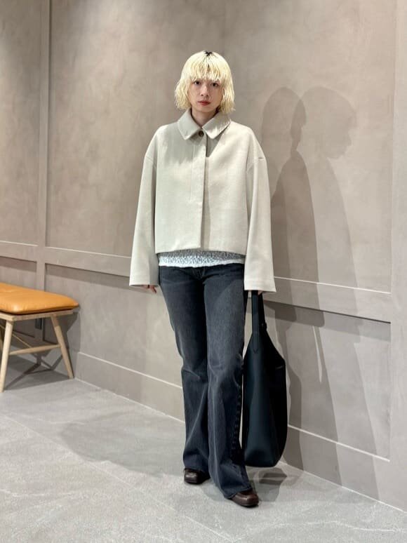 ステンカラーコートとデニムパンツを着た女性