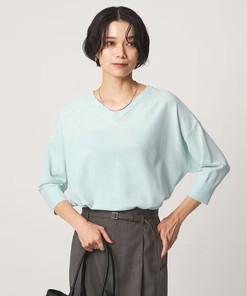 襟元の開いたニットを着た女性